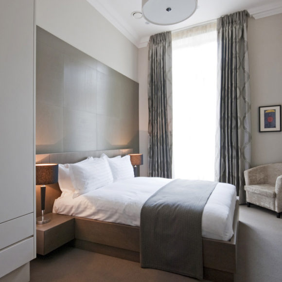 Camera in hotel a Londra con parete in rovere spazzolato e armadio laccato bianco.